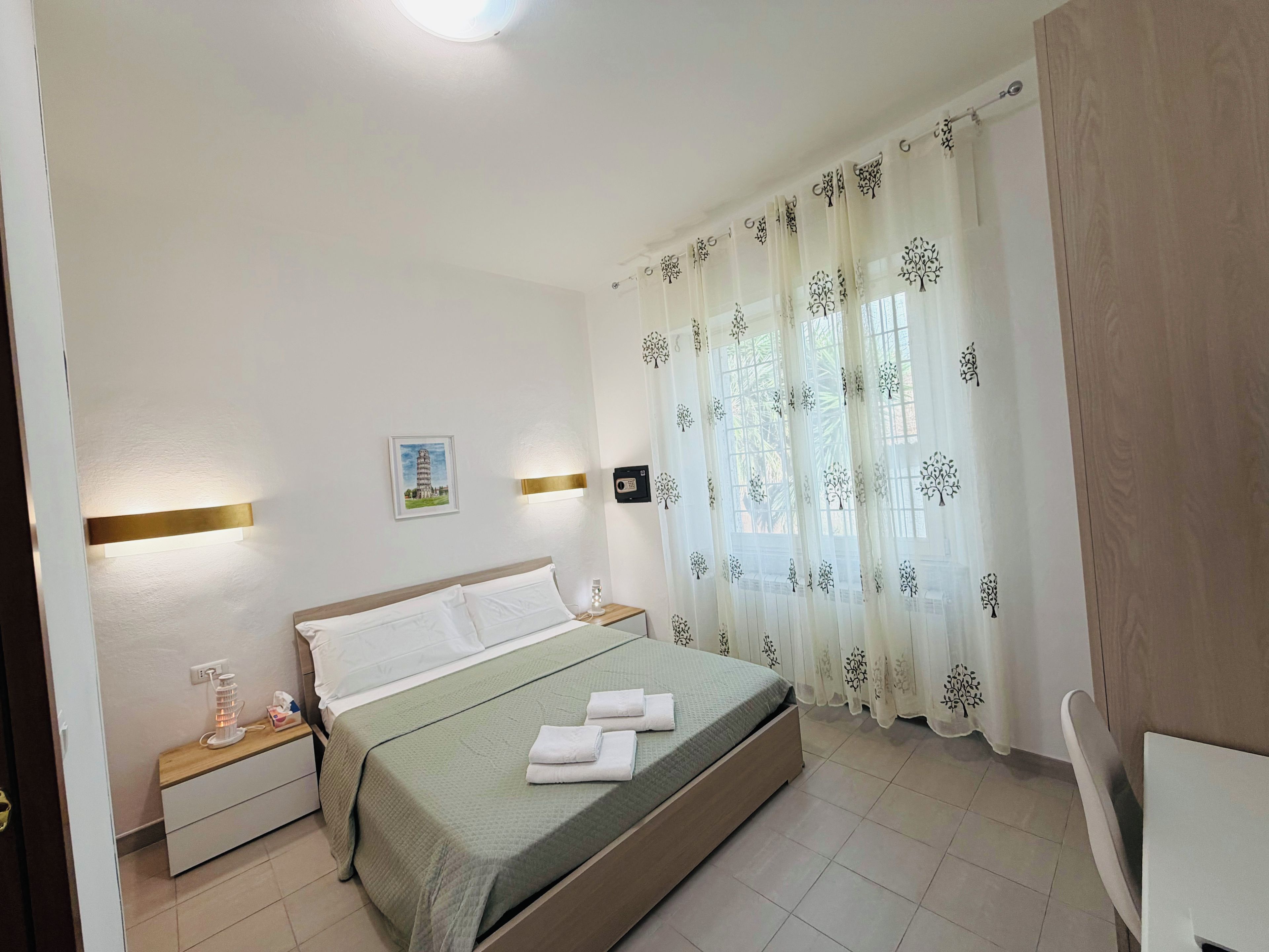 Una habitación de hotel con cama, mesita de noche, lámpara y cortinas.