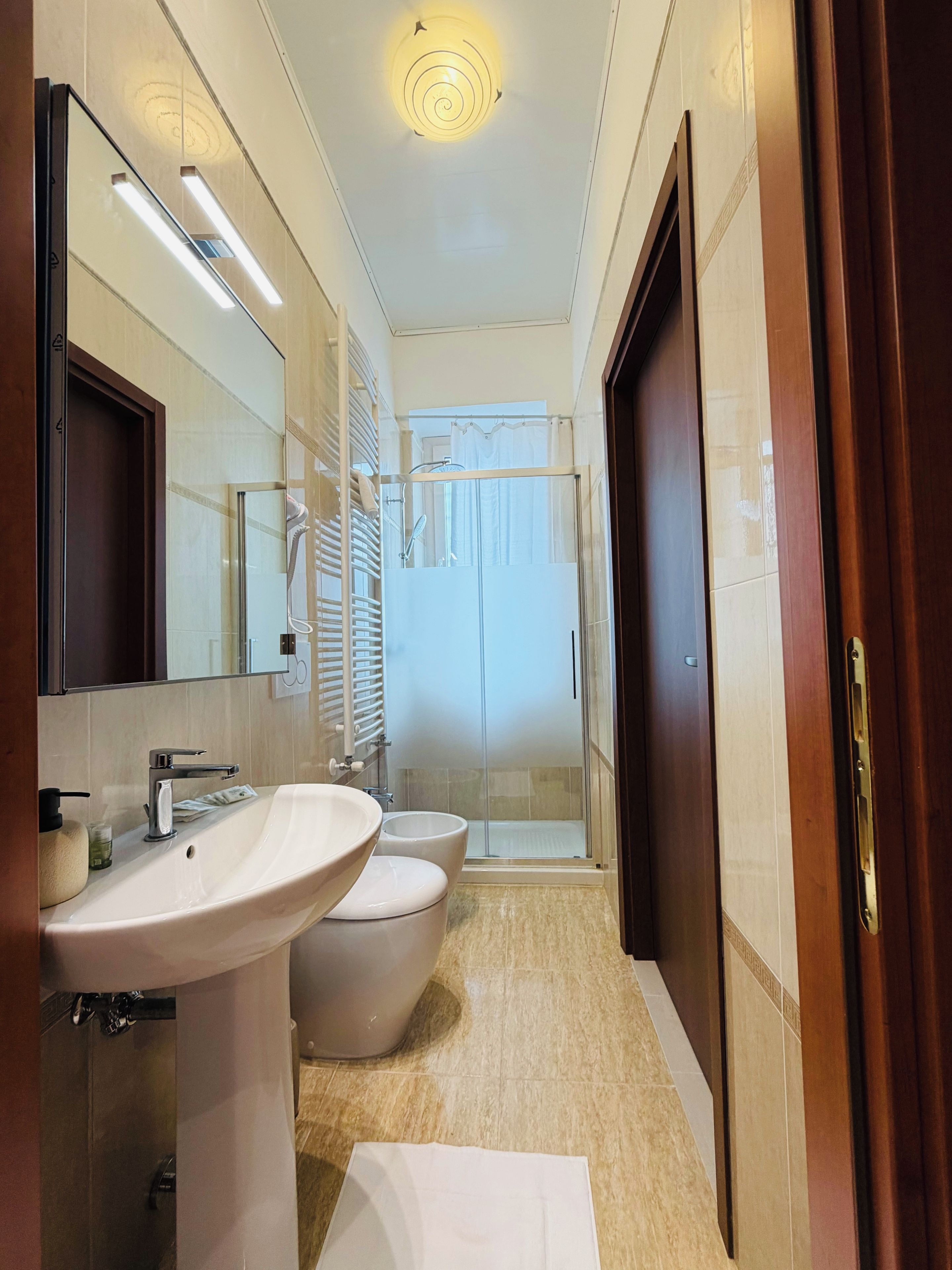 Un baño moderno con un espejo grande, dos lavabos, ducha y un inodoro.