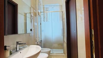 Un baño moderno con un espejo grande, dos lavabos, ducha y un inodoro.