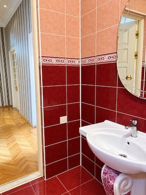 A bathroom with a white sink, red tiles, and a mirror. - Alina Central Hostel (Baku)