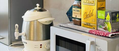 A kitchen with a coffee maker, a microwave, and boxes of tea on the counter.
