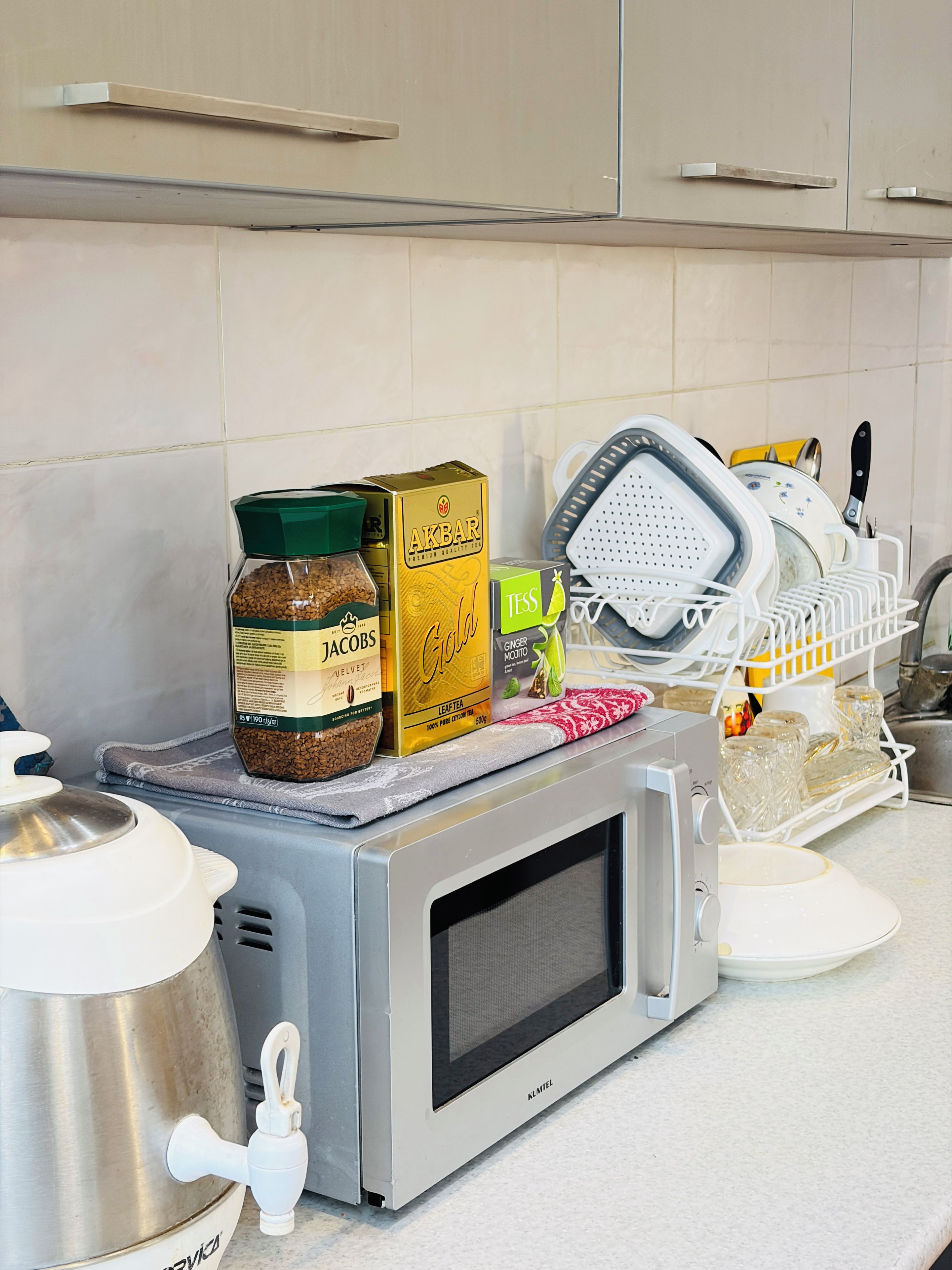 Een keuken met een magnetron, een waterkoker en verschillende etenswaren op het aanrecht.