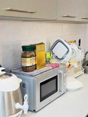 A kitchen with a microwave, a kettle, and various food items on the counter. - Alina Central Hostel (Baku)