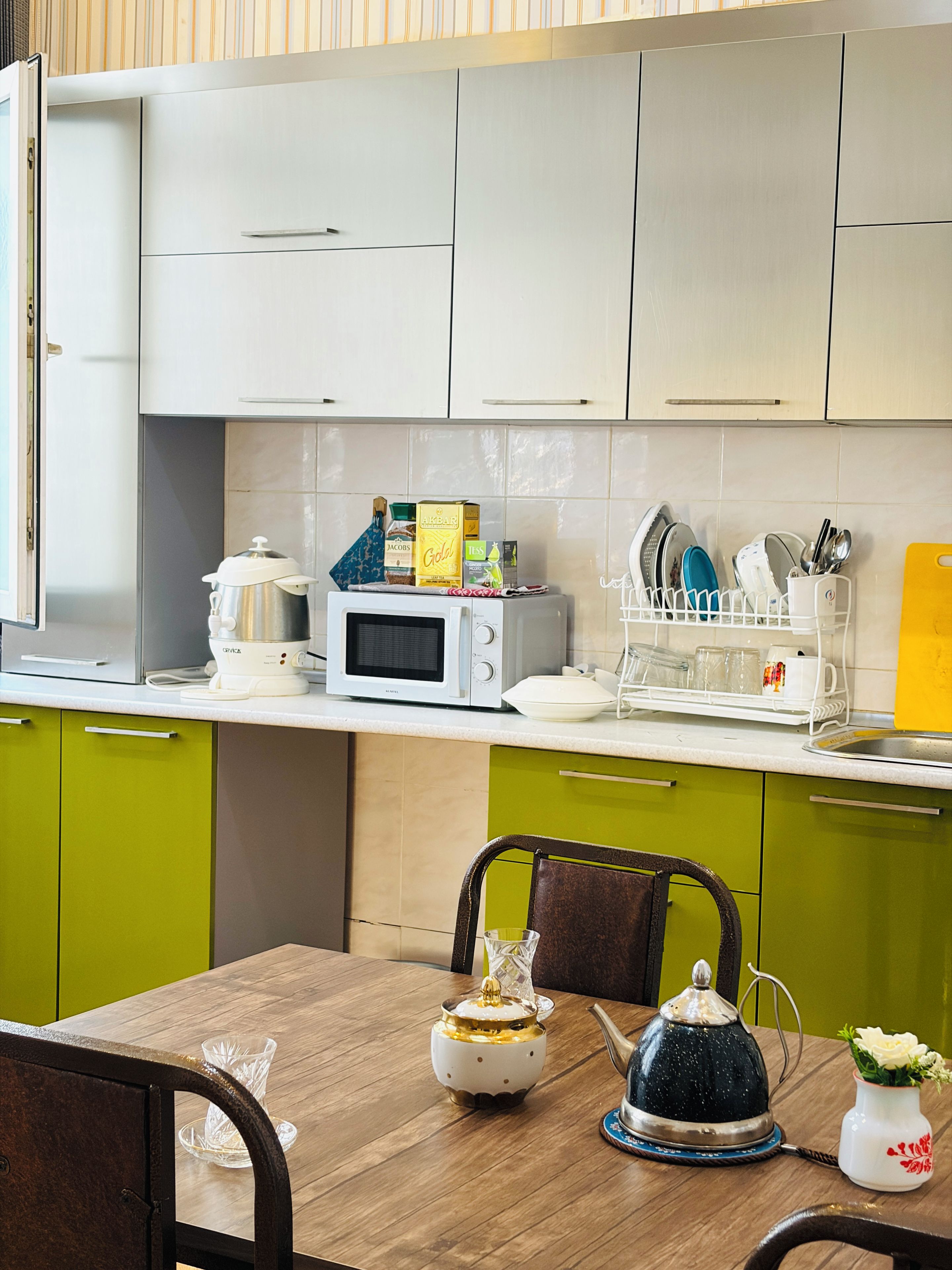 Una cocina con microondas, cafetera y diversos utensilios sobre la encimera.