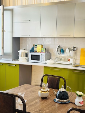 A kitchen with a microwave, coffee maker, and various kitchen items on the counter. - Alina Central Hostel (Baku)