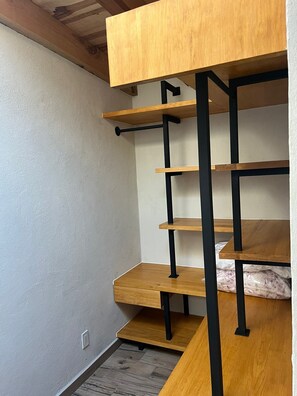 A corner of a room with a wooden bunk bed and a black metal ladder.