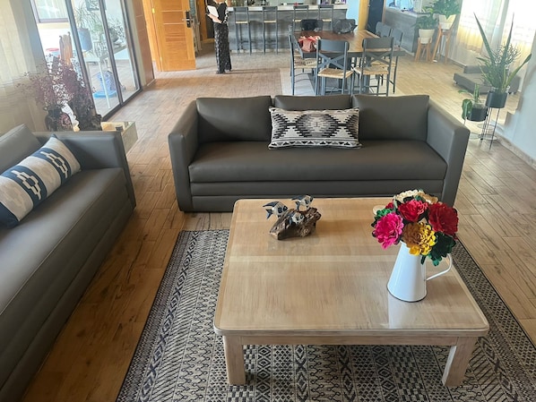 A modern living room with a grey sofa, a wooden coffee table, and a vase of flowers.