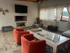 A living room with a fireplace, a sofa, a coffee table, and a TV mounted on the wall.