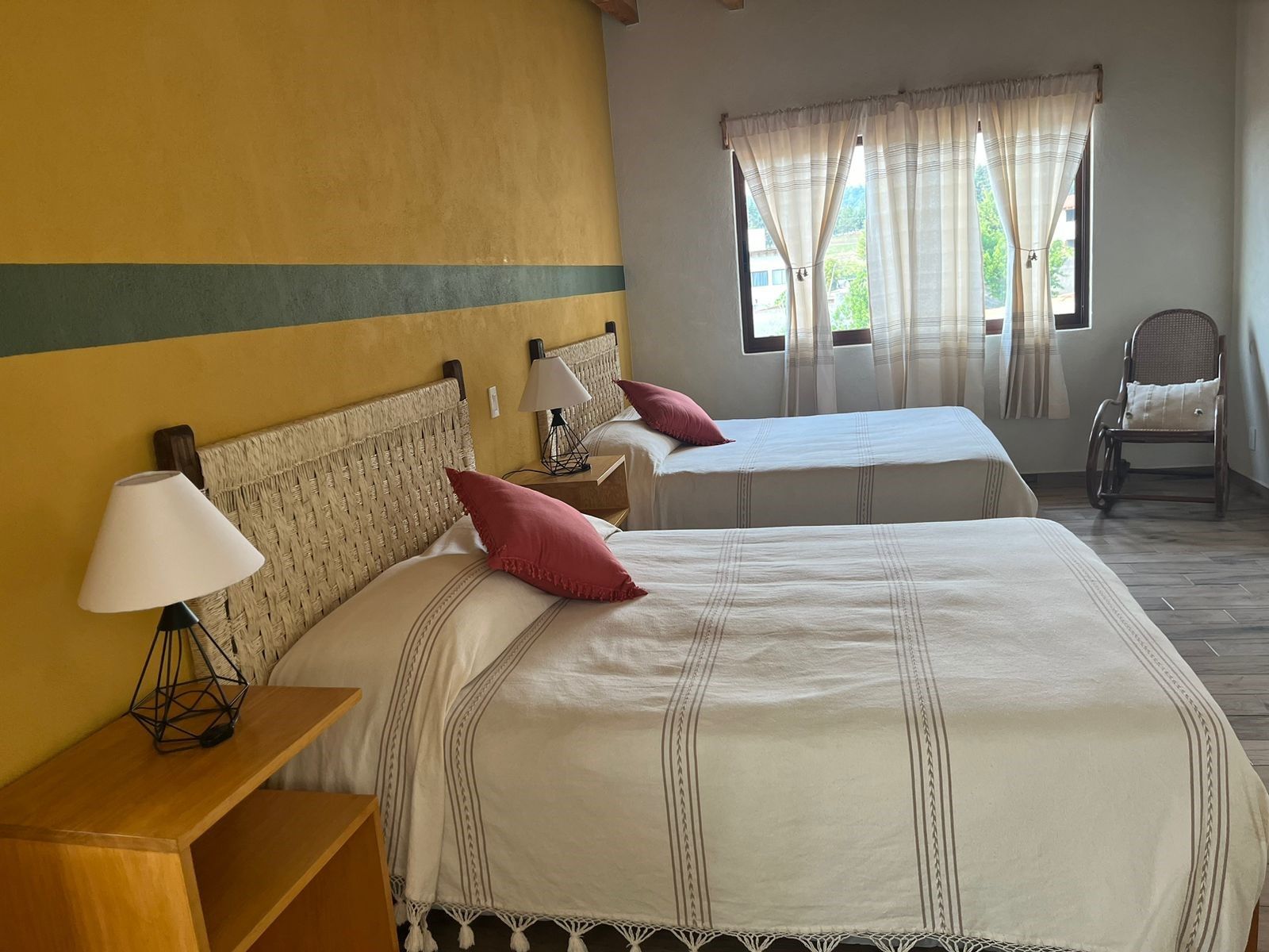A double room with two beds, a chair, a nightstand, and a lamp.