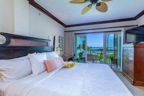 A hotel room with a large bed, a television, and a view of the ocean through the balcony doors. - Shoshone Condominums (Big Sky)