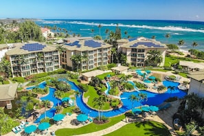 A resort with multiple buildings, a large pool area with various water features, and a view of the ocean. - Shoshone Condominums (Big Sky)
