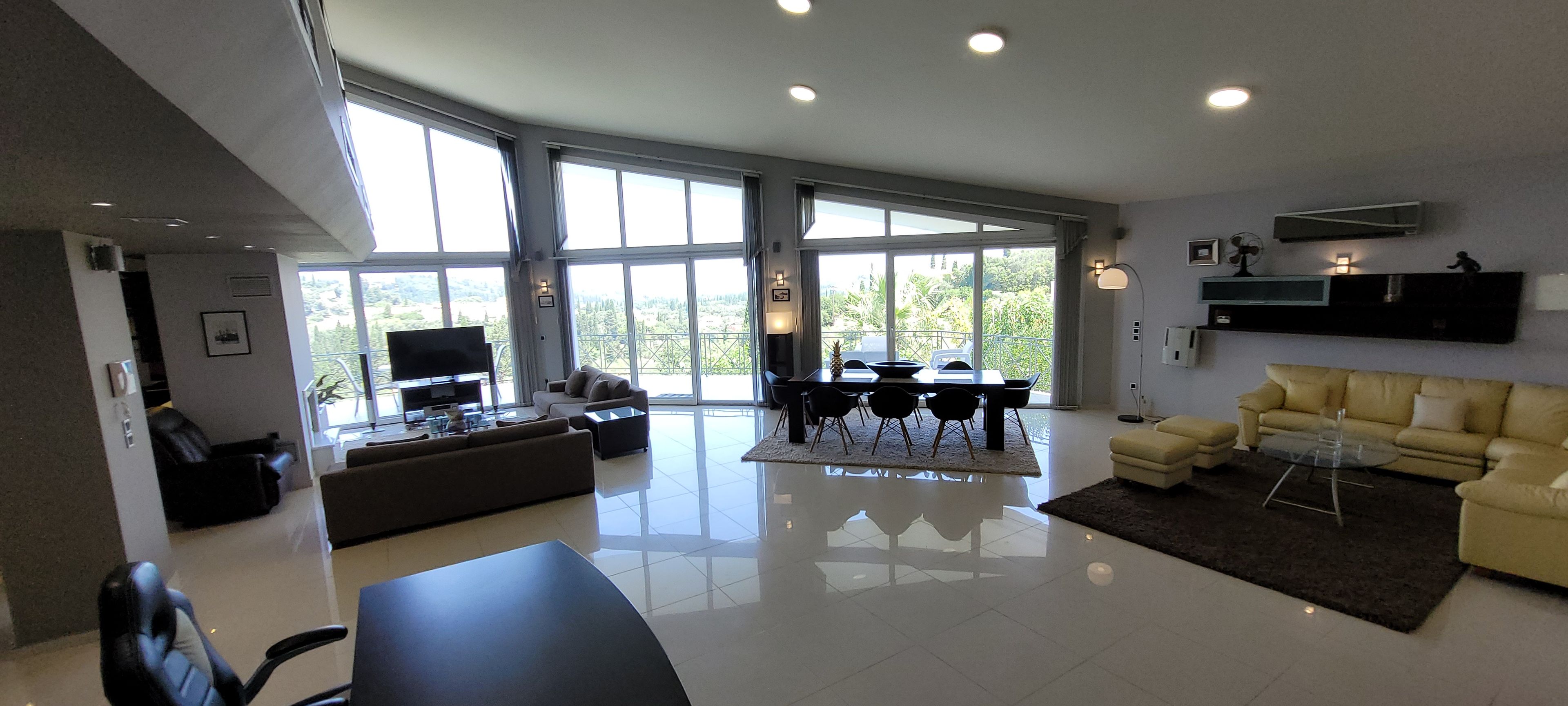 Un amplio salón con un gran ventanal, un televisor de pantalla plana, un sofá, una mesa de comedor y un sofá amarillo.