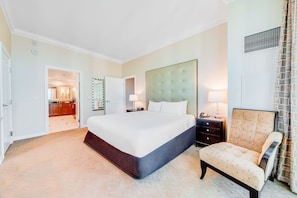 A hotel room with a large bed, a bedside table, a chair, and a bathroom visible through an open door. - Vista Balcony Collection MGM Signature (Las Vegas)