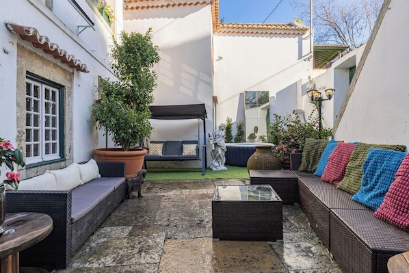 An outdoor seating area with wicker furniture, a potted plant, and a statue. - Big Double Room with Patio BBQ Snooker in Center (Sintra)