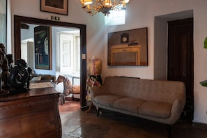 A room with a wooden dresser, a sofa, a mirror, and a clock on the wall. - Big Double Room with Patio BBQ Snooker in Center (Sintra)