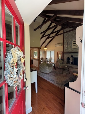 A room with a red door, wooden beams, a fireplace, and a chandelier. - Relaxing Vineyard Retreat, FREE CAR, Fenced yard, Pet Friendly, Sleeps 10! (West Tisbury)