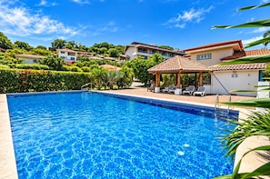A swimming pool with a tiled deck, lounge chairs, and a gazebo. - Casa Arcos - Coastal Escape - Entire House & Attached Apartment 5 Min Beach Walk (Playa Hermosa)
