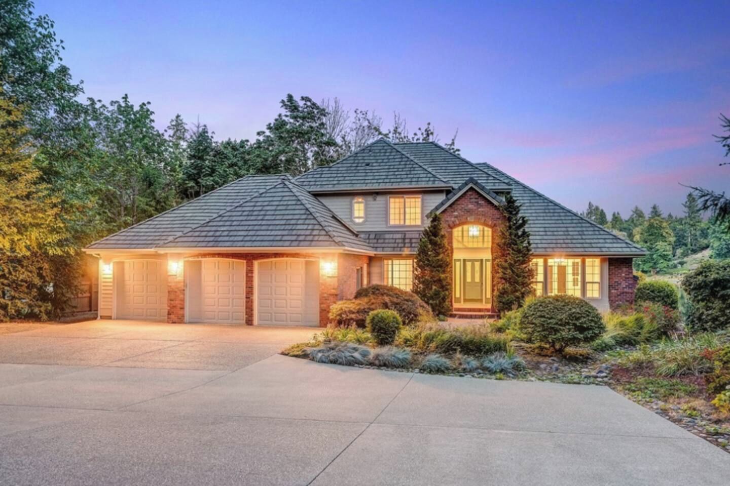 Une maison à deux étages avec un garage, un porche à l’avant et une allée.