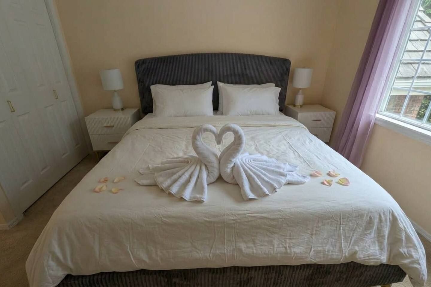 Une chambre d’hôtel avec un lit, deux tables de chevet et une fenêtre avec des rideaux.