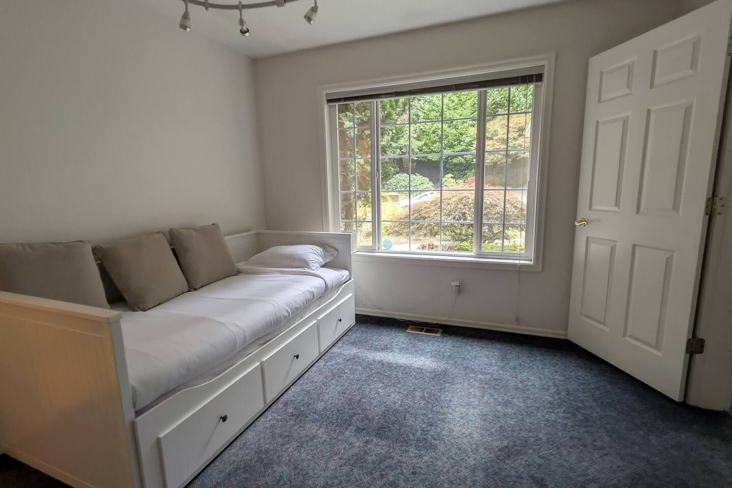A bedroom with a bed, a window, and a door.