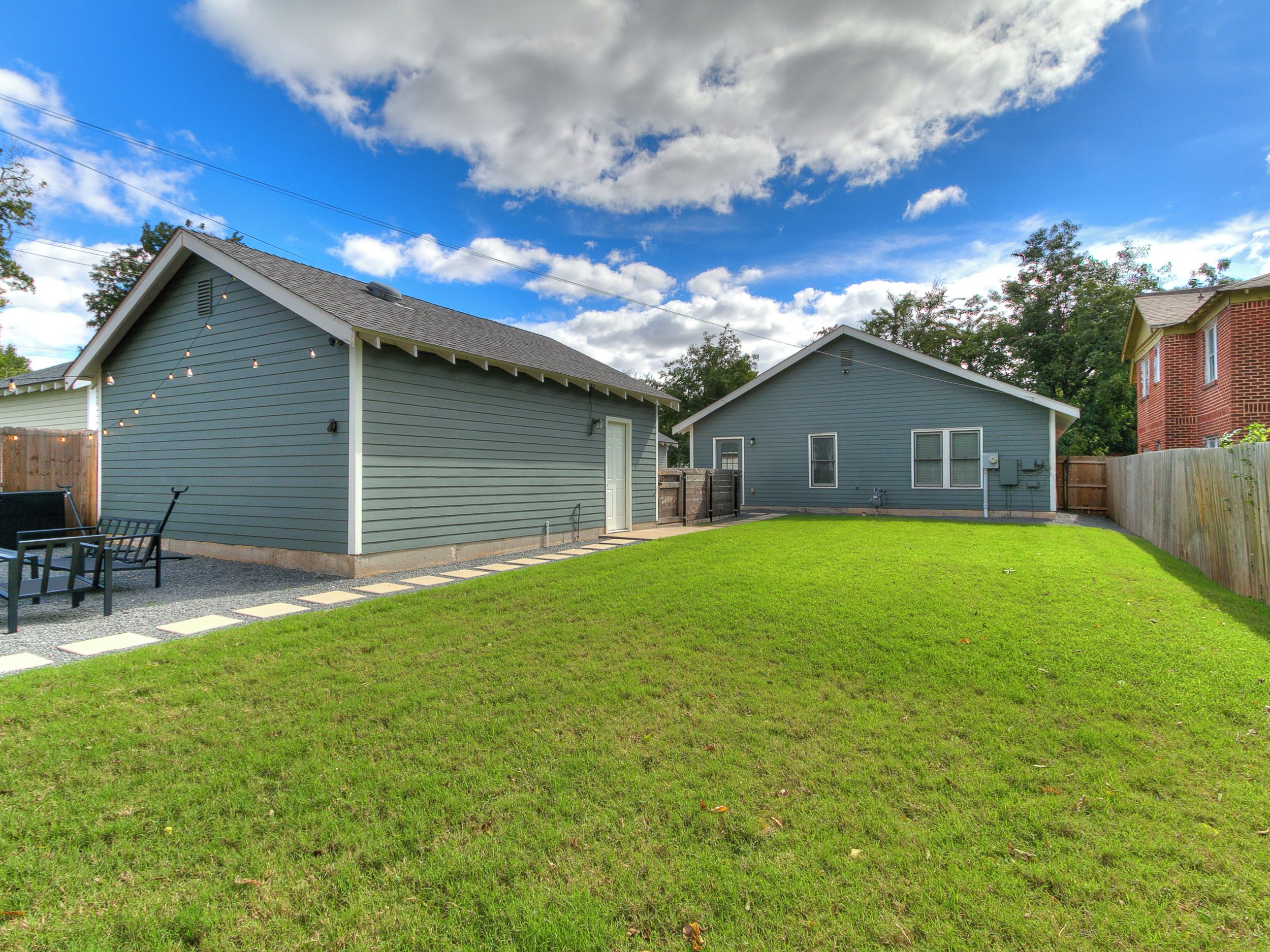 A residential property with a well-maintained lawn, a patio area with outdoor furniture, and a garage.