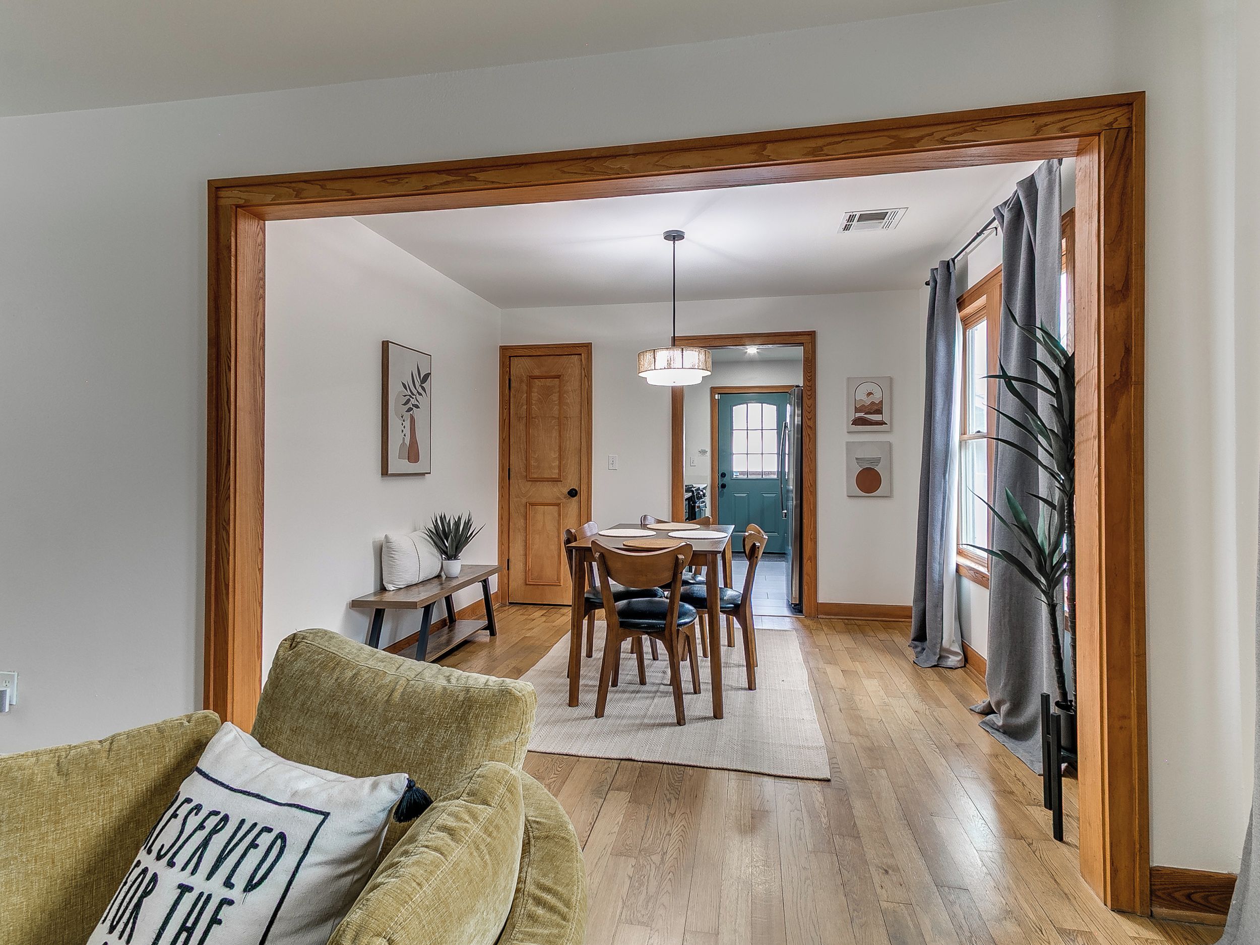 A dining area with a wooden table and chairs, a bench with cushions, and a door leading to another room.