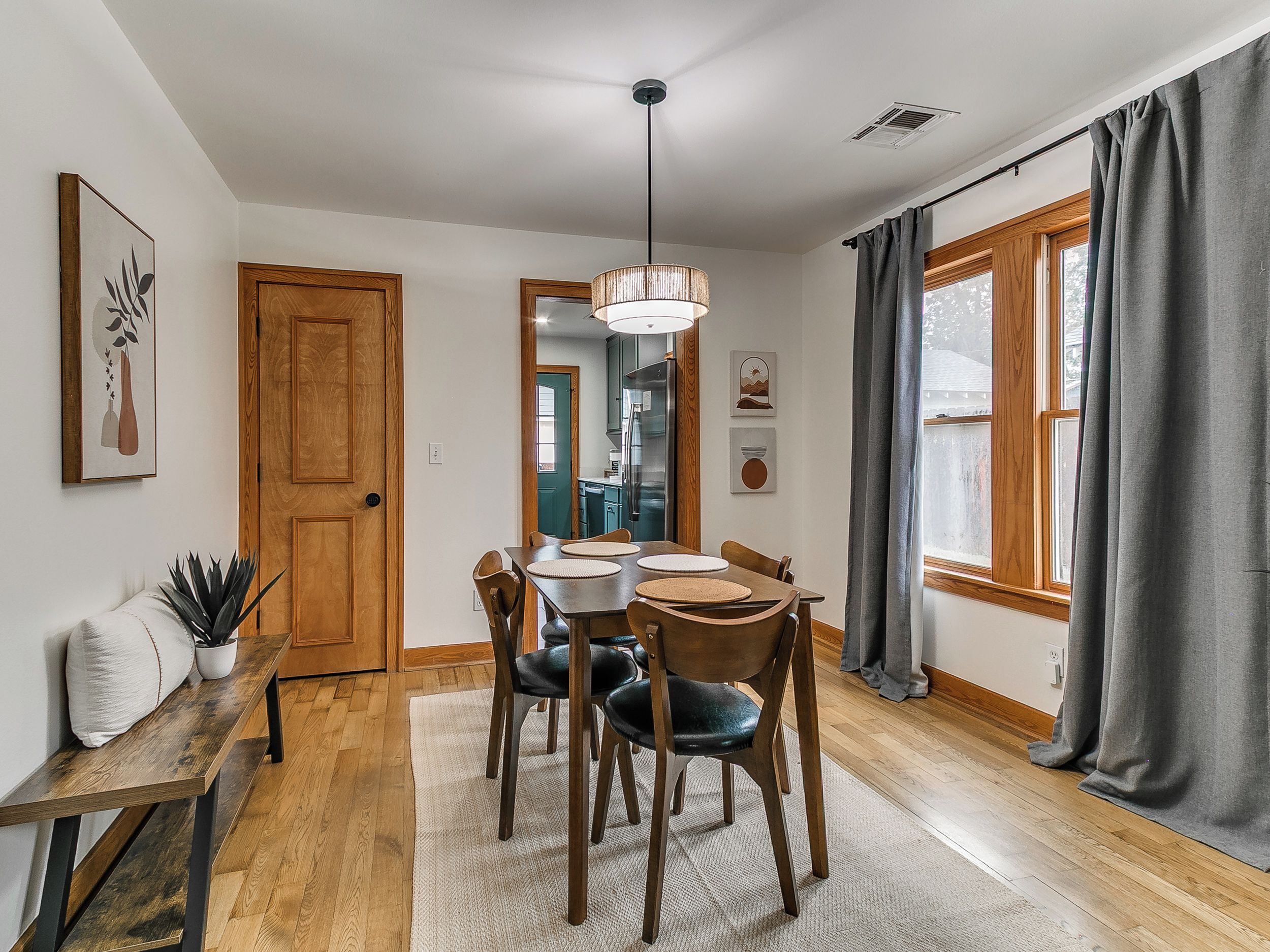 A dining area with a wooden table and chairs, a bench, and a hanging light fixture.