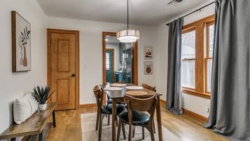 A dining area with a wooden table and chairs, a bench, and a hanging light fixture.