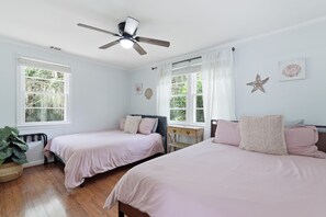 A bedroom with two beds, a ceiling fan, and large windows. - Lowcountry Cottage w/ Firepit - Near Downtown (Beaufort)