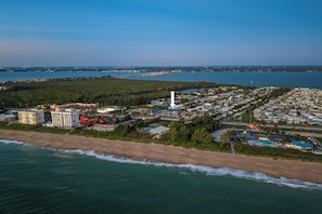 An aerial view of a coastal resort with beachfront properties, a marina, and a prominent white tower. - 2-bedroom townhome Island living Canal front Walk to the BEACH (Jensen Beach)