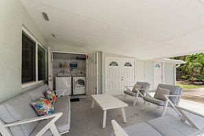 A covered outdoor seating area with a sofa, chairs, and a table. - 2-bedroom townhome Island living Canal front Walk to the BEACH (Jensen Beach)