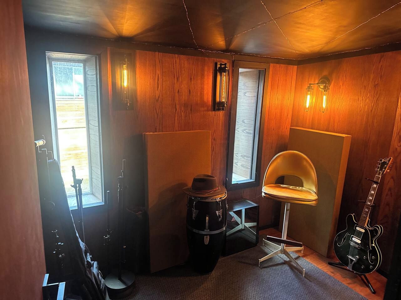 Een kamer met houten wanden, een drumstel, een gitaar en een stoel.