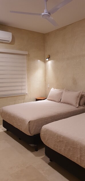A bedroom with two beds, a ceiling fan, an air conditioning unit, and a bedside table with a lamp. - Vista Tortuga - Villa DUNA by the beach - rooftop - heated Pool (Todos Santos)