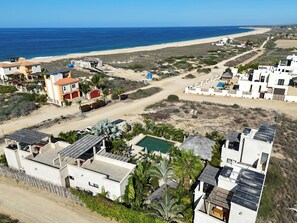 A coastal residential area with modern houses, a swimming pool, and a beach in the background. - Vista Tortuga - Villa DUNA by the beach - rooftop - heated Pool (Todos Santos)