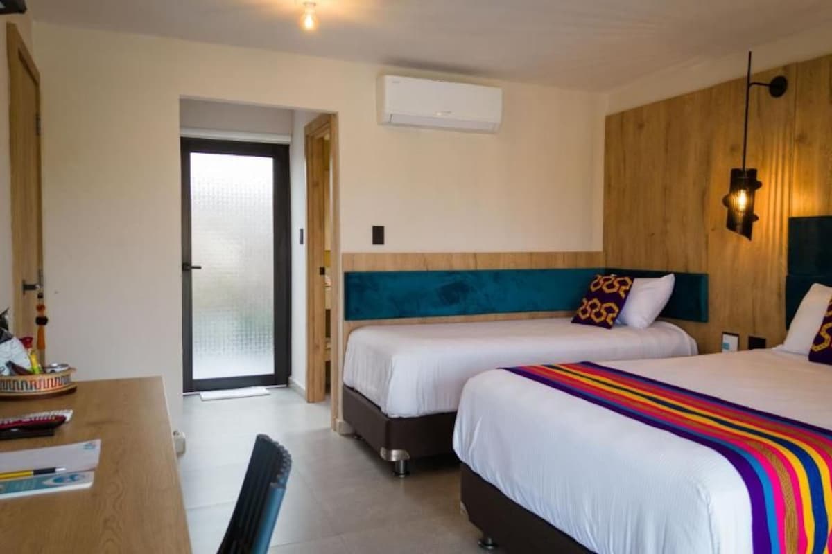 Une chambre d’hôtel avec deux lits, un bureau et une porte donnant sur un balcon.