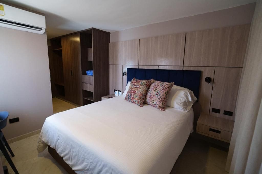 Una habitación de hotel con una cama, un armario y aire acondicionado.
