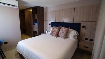 Una habitación de hotel con una cama, un armario y aire acondicionado.