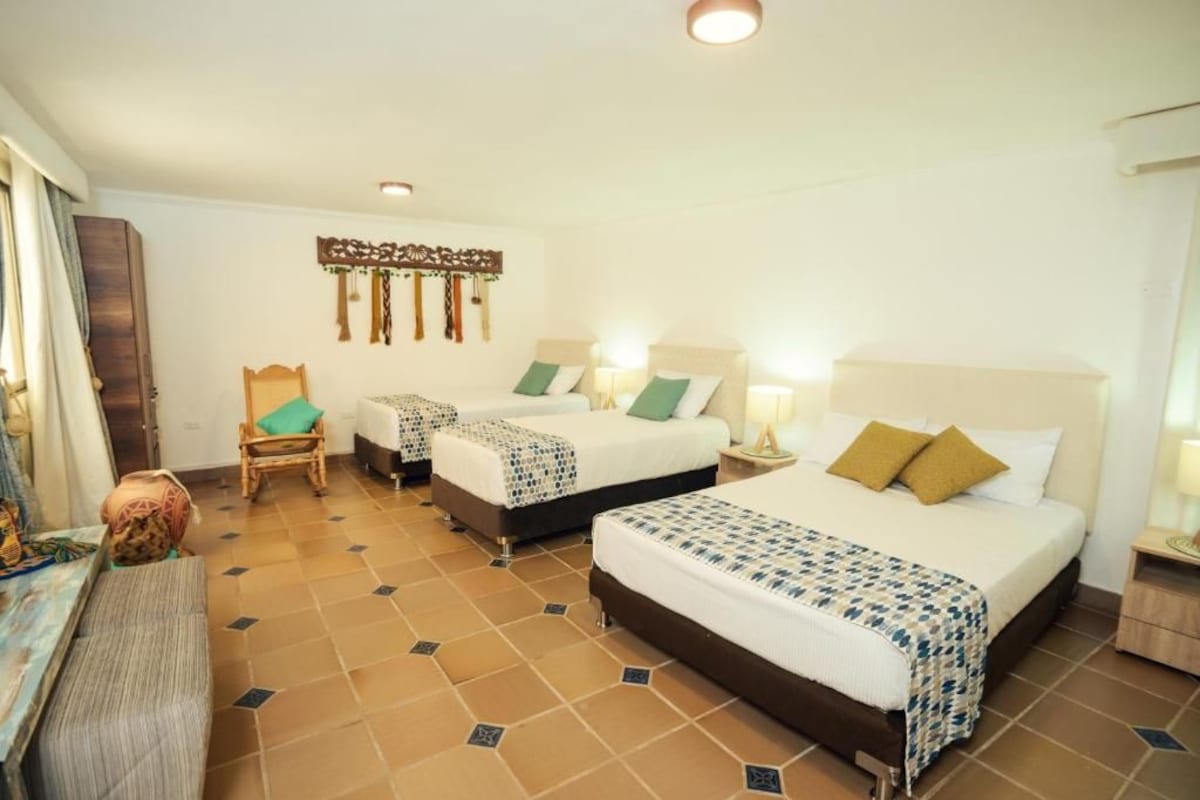 Une chambre d’hôtel avec deux lits, une chaise, un bureau et un élément décoratif mural.