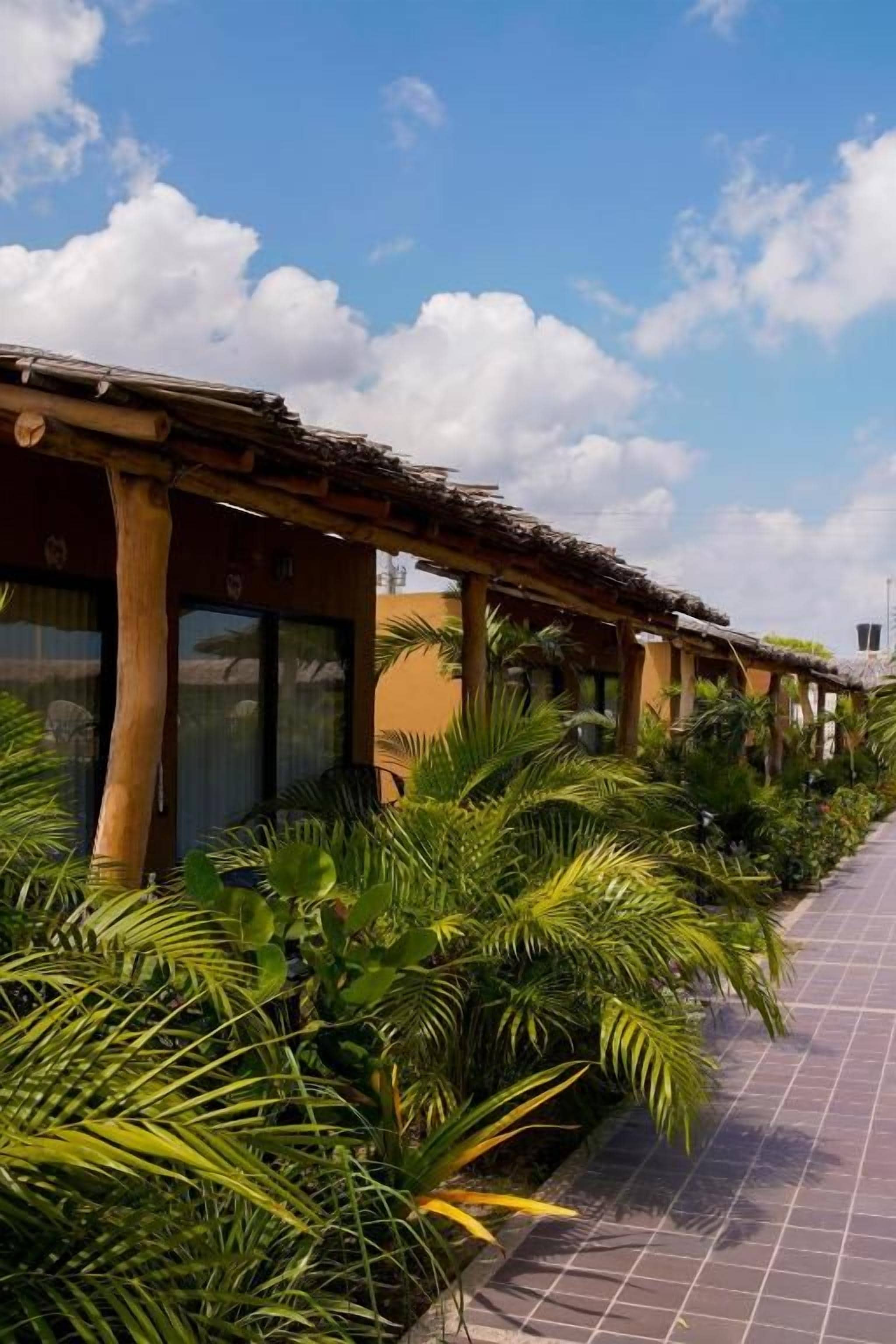 A building with a covered walkway, surrounded by lush tropical plants.