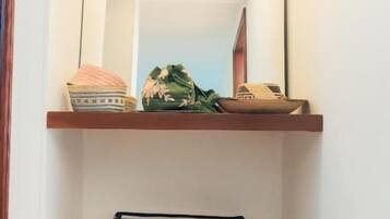 A narrow hallway with a mirror, a shelf with a decorative item, and a drying rack.