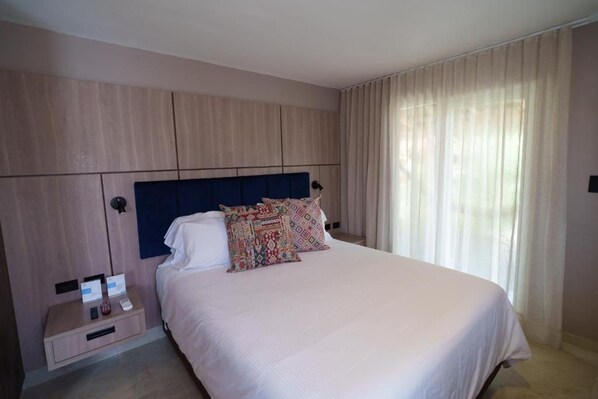 A hotel room with a bed, a nightstand, and a headboard.