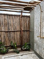 Zona de ducha con techo de madera y pared con diseño.