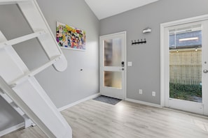 A room with a grey wall, a white door, and a colorful artwork. - NEW King with Loft Beach Near Gulf (Gulfport)