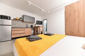 Ein modernes Schlafzimmer mit Bett, Küchenzeile und einer Wand aus Holzpaneelen.