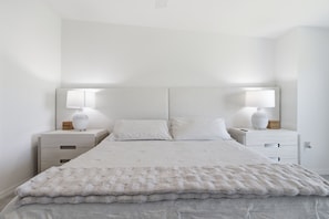A neatly made bed with a white duvet and pillows, flanked by two bedside tables with lamps, in a room with white walls and a simple, clean design. - Course side Condo - 2BR + Den - Golf Membership Included; Calusa Country Club (Bradenton)