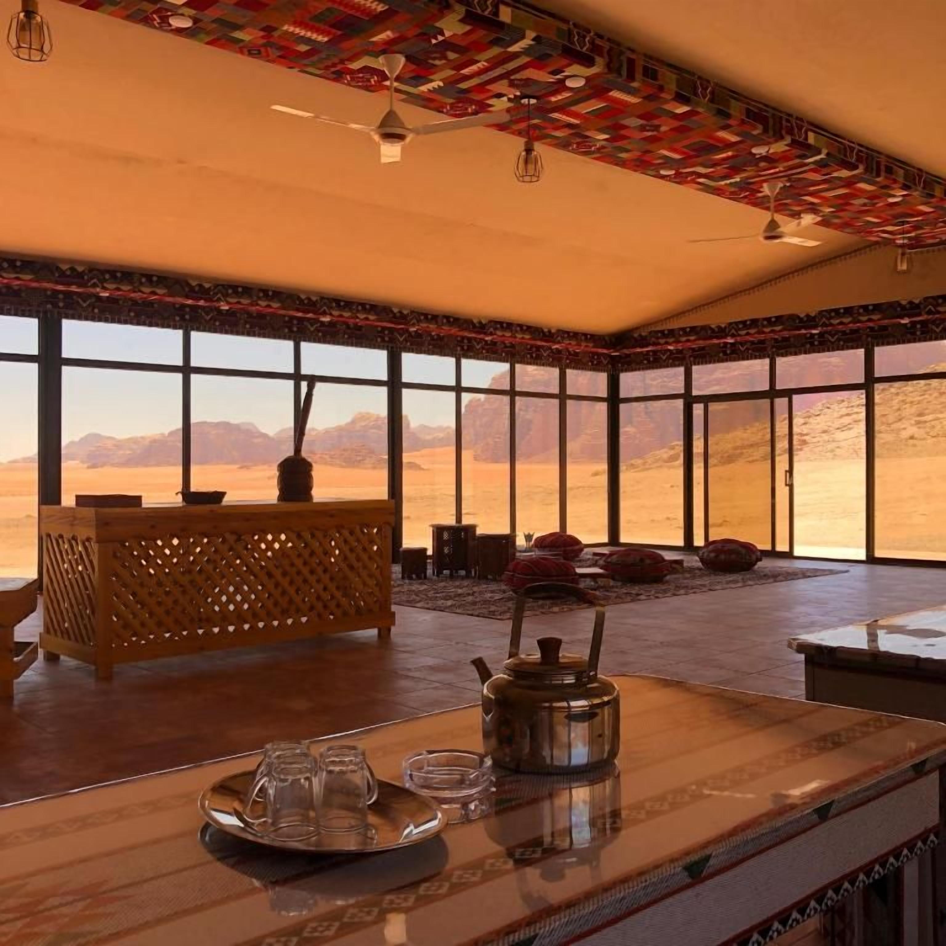 Una habitación con ventanas amplias, una mesa de madera con una bandeja y un ventilador de techo.