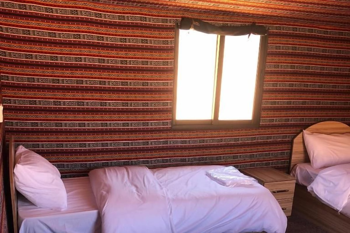Una habitación con dos camas, una ventana y un papel tapiz decorado.