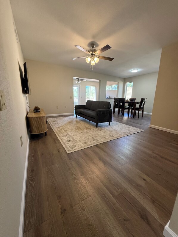 A spacious living area with a dark-colored sofa, a dining table with chairs, and a ceiling fan. - Come for the Views, Stay for the Escape (Green Valley)