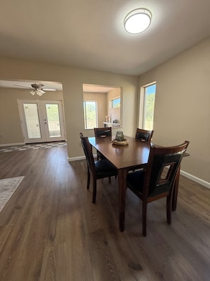 A dining area with a wooden table and chairs, a ceiling fan, and a view of the outdoors through a window. - Come for the Views, Stay for the Escape (Green Valley)
