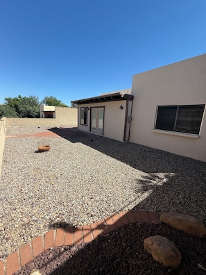 A building with a gravel patio, a brick border, and a small structure with a door and windows. - Come for the Views, Stay for the Escape (Green Valley)